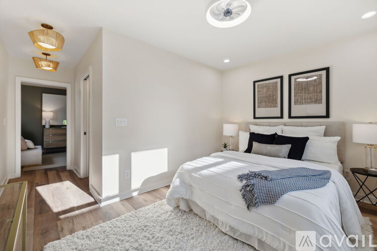 A bedroom with a bed, two lamps, and two pictures on the wall.