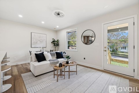 A living room with a white couch and a round mirror on the wall.