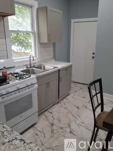 A kitchen with a white stove top oven and a marble counter top.