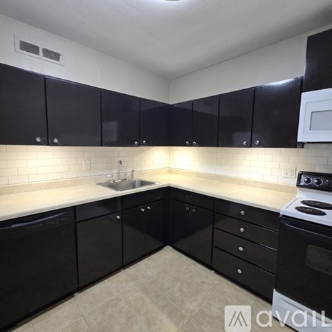 A kitchen with black cabinets and a white stove.