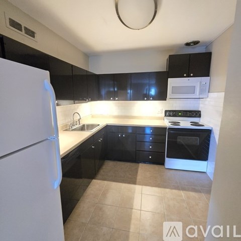 A kitchen with black cabinets and a white refrigerator.