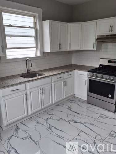 A kitchen with white cabinets and marble countertops.