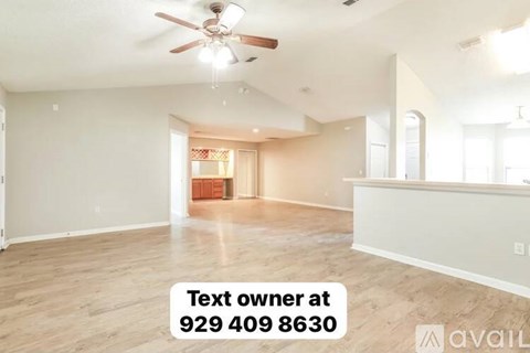 A spacious room with a ceiling fan and a text box indicating the owner's contact information.