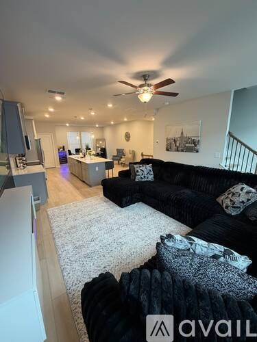 A living room with a black couch and a ceiling fan.