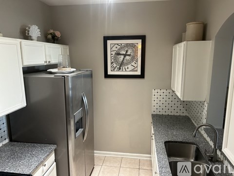 A kitchen with a fridge, a sink and a clock on the wall.