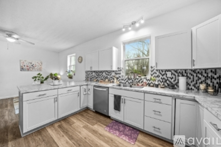 A kitchen with white cabinets and a black and white tiled backsplash.