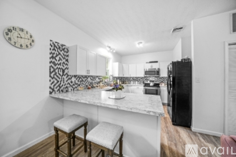 A kitchen with a marble countertop and a black and white patterned backsplash.