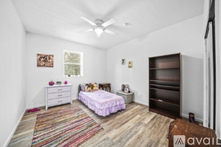 A bedroom with a bed, dresser, and a ceiling fan.