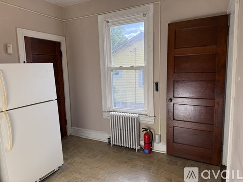 A white fridge in a room with a window and a door.