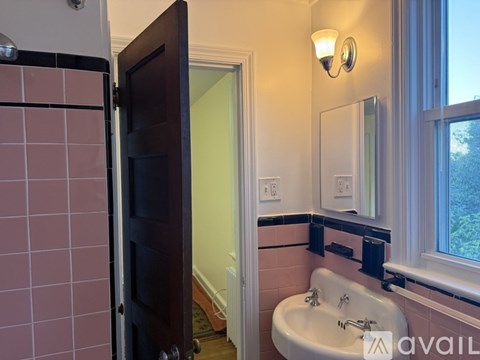 A bathroom with a pink tiled shower and a white bathtub.