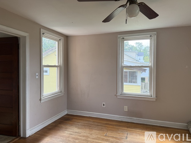 A room with a ceiling fan and two windows.