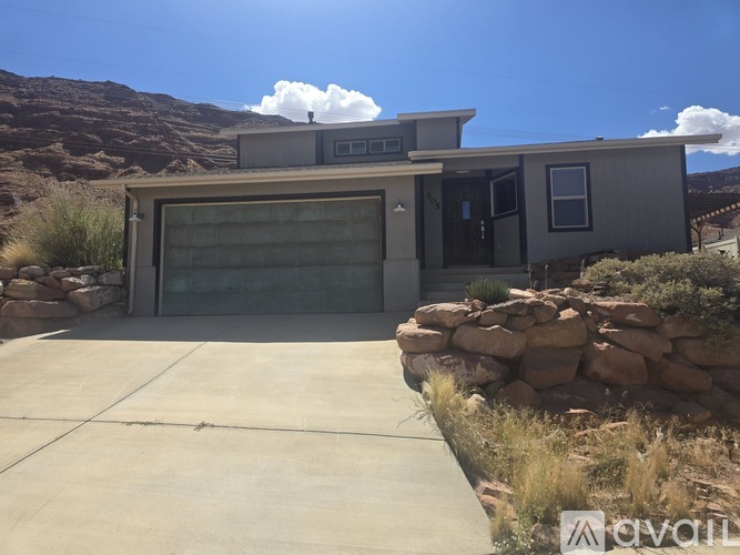 A modern house with a garage door and a stone wall in front.
