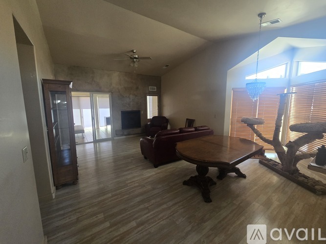 A living room with a wooden floor and a large window with blinds.