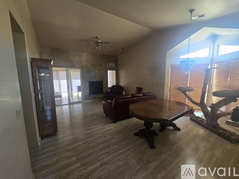 A living room with a wooden floor and a large window with blinds.