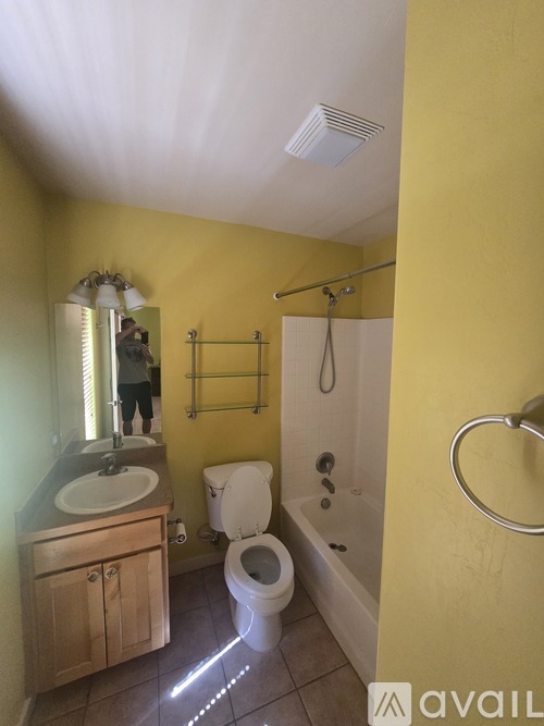 A bathroom with yellow walls has a toilet, sink, and shower.