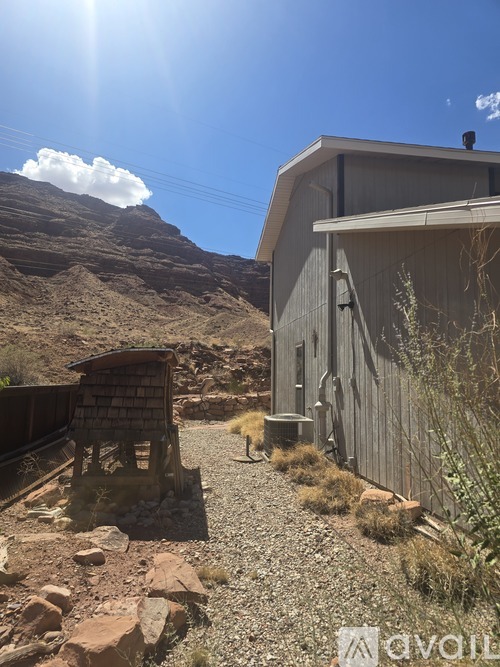 A gravel path leads to a wooden structure in a desert-like environment.