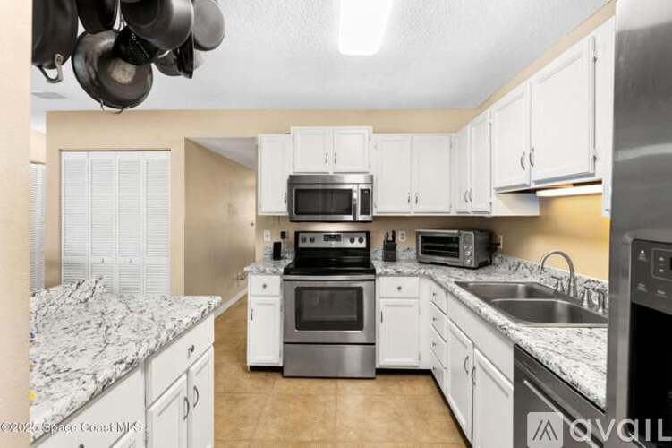 A kitchen with white cabinets and a granite countertop.