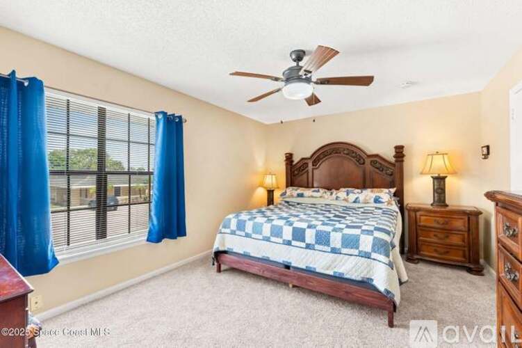 A bedroom with a bed, dresser, and window with blue curtains.