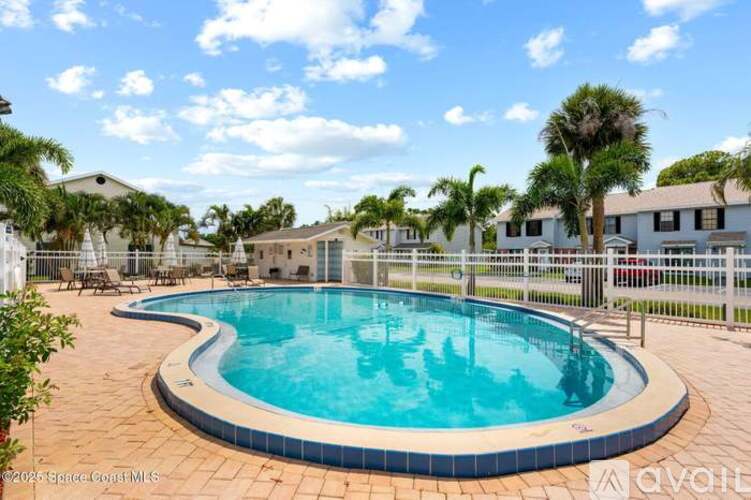 A swimming pool surrounded by a fence and palm trees.
