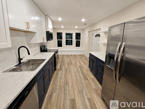 A modern kitchen with dark blue cabinets and stainless steel appliances.