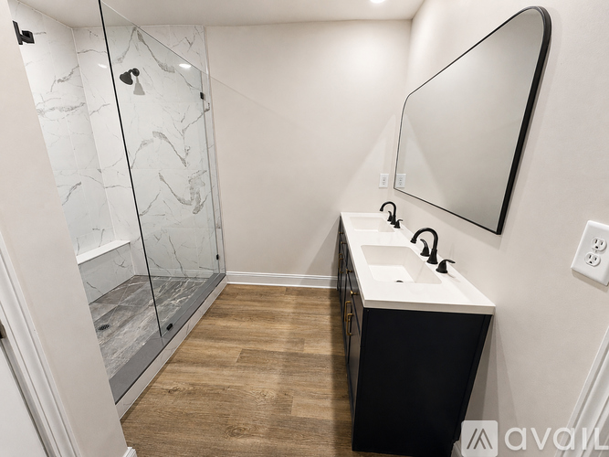 A bathroom with a marble shower and a wooden floor.