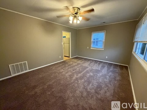 A room with a ceiling fan and carpeted floor.