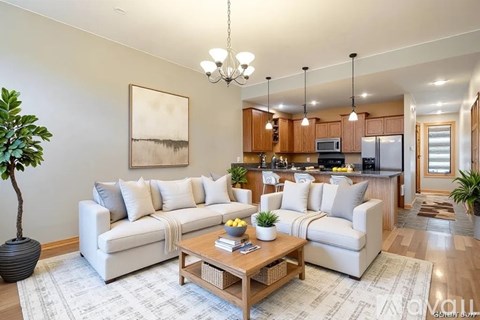 A well-lit living room with a white sofa, wooden coffee table, and a painting on the wall.