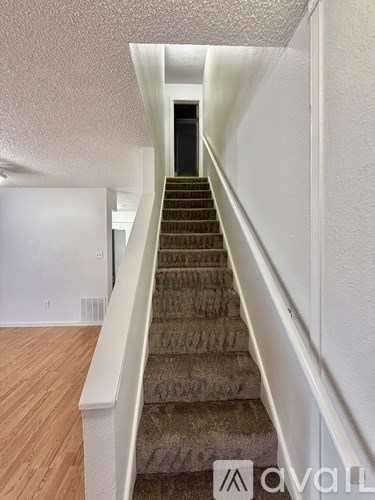 A staircase with a carpeted runner and white handrails.