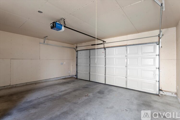 A spacious garage with a white door and a security camera mounted on the ceiling.