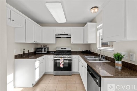 A kitchen with white cabinets and a black stove top oven.