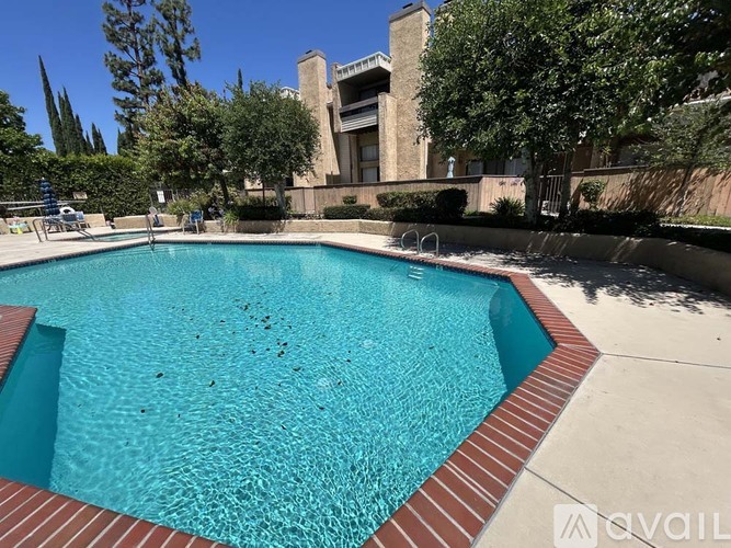 A pool surrounded by a brick border with a building in the background.