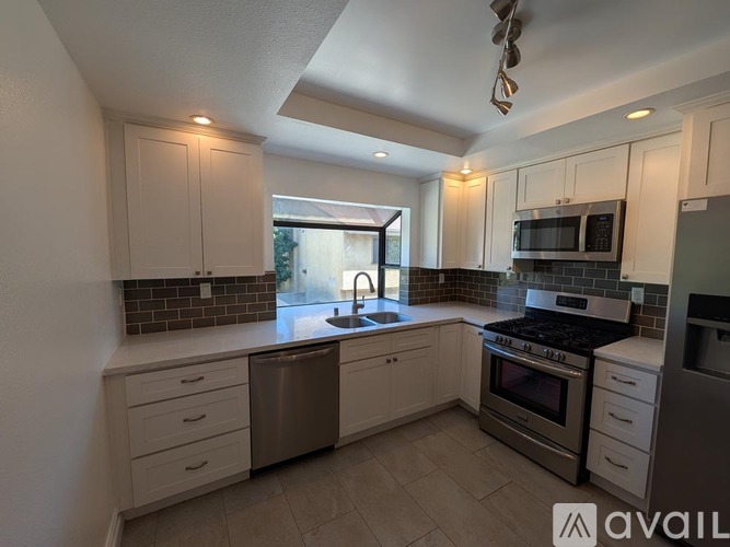 A kitchen with white cabinets and a stainless steel dishwasher.