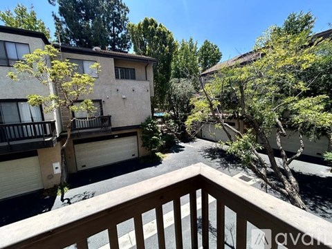 A balcony view of apartment buildings with trees in the foreground.