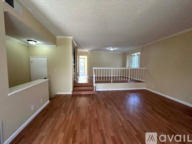 A spacious room with wooden floors and white railings.