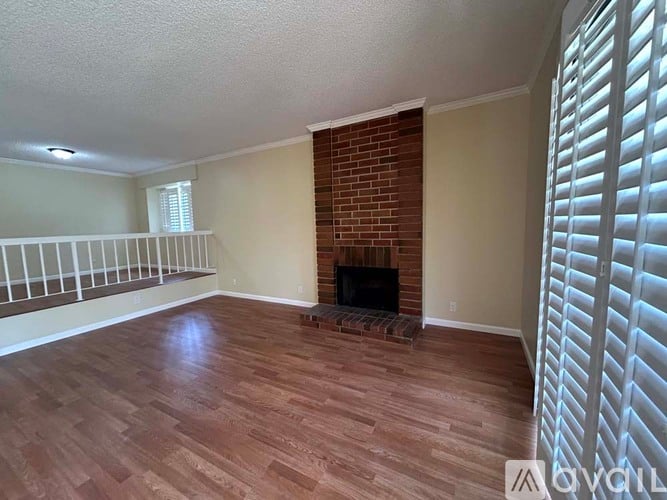 A living room with a fireplace and wood flooring.