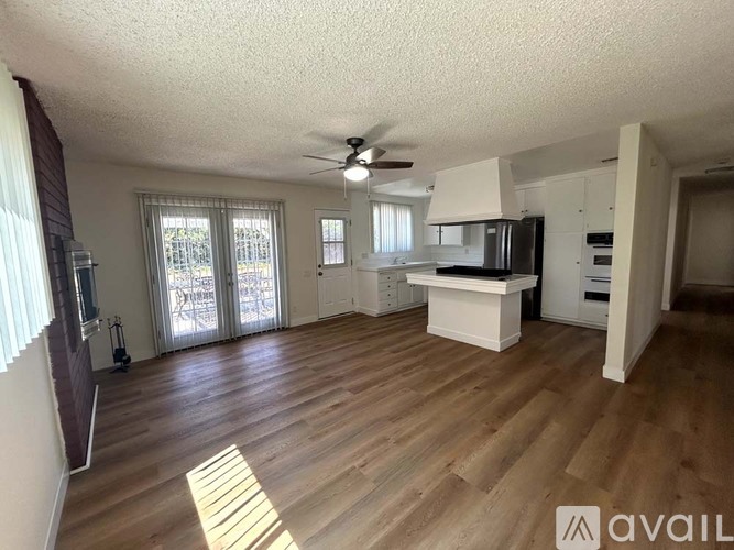 A spacious living room with wooden flooring and a ceiling fan.