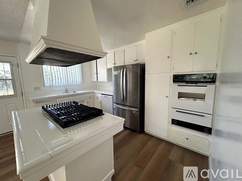 A modern kitchen with white cabinets and a stainless steel refrigerator.