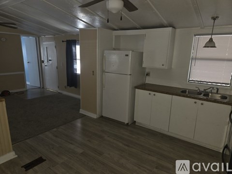 A kitchen with a white refrigerator and wooden floors.