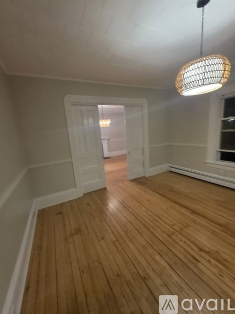 A room with wooden floors and a hanging light fixture.