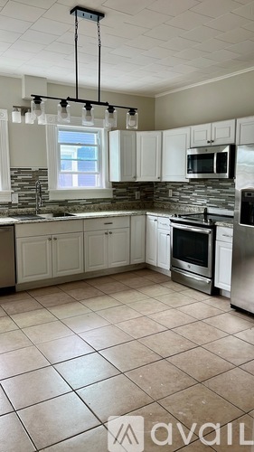 A kitchen with white cabinets and a stone backsplash.