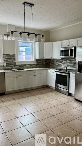 A kitchen with white cabinets and a stone backsplash.