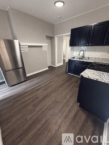 A kitchen with black cabinets and a stainless steel refrigerator.