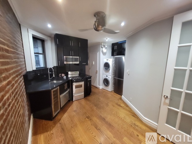 A kitchen with black cabinets and a wooden floor.