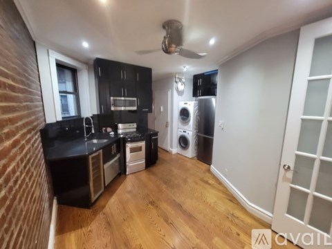 A kitchen with black cabinets and a wooden floor.