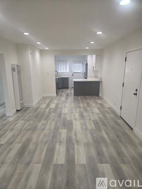 A spacious room with wooden flooring and white walls.