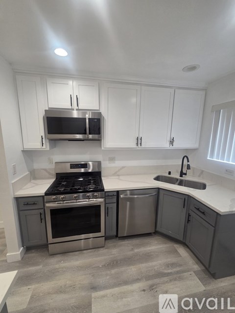 A kitchen with a stove, oven, microwave, and cabinets.