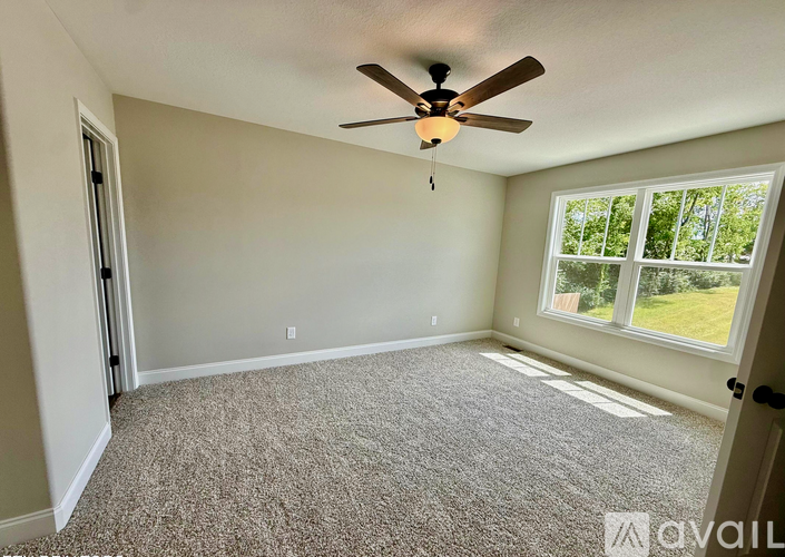 A room with a ceiling fan and carpeted floor.
