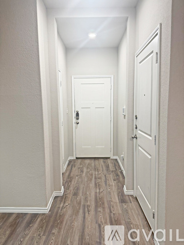 A hallway with a white door and wooden floors.
