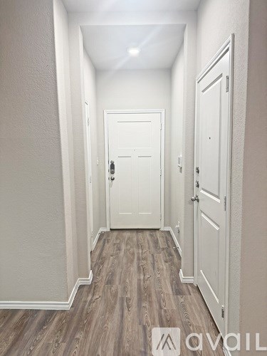 A hallway with a white door and wooden floors.