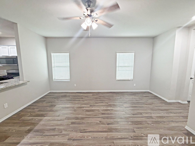 A room with a ceiling fan and wooden flooring.
